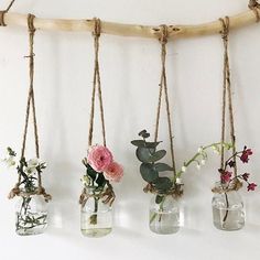 four vases filled with flowers hanging from rope