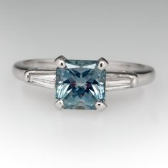 an aqua and white gold engagement ring with baguets on the side, set with a blue topazte