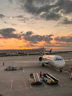 an airplane is parked on the tarmac at sunset