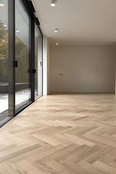 an empty room with wooden floors and large windows