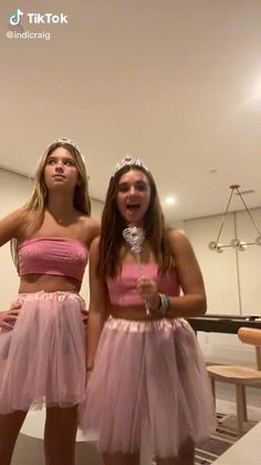 two girls in pink dresses standing next to each other with their hands on their hips