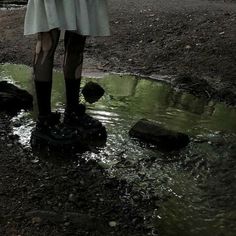 a woman standing on top of a puddle holding an umbrella