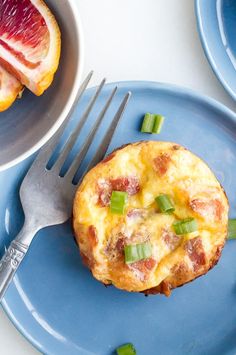 a blue plate topped with an omelet covered in bacon and green onions next to a fork