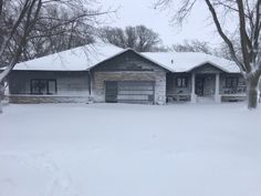 a house that is covered in snow and has trees on both sides of the house