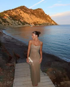 a woman standing on a wooden walkway next to the ocean