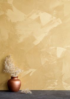 a vase with some white flowers in it on a table next to a yellow wall