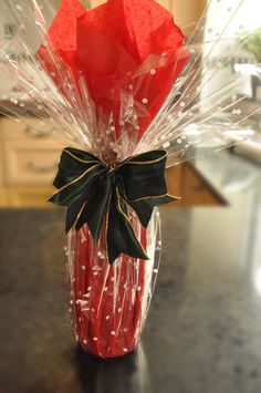 a vase filled with red flowers and wrapped in plastic wrap on top of a table