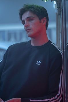 a young man with green hair wearing a adidas sweatshirt and looking off into the distance