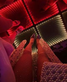 the legs and feet of a woman in red tights are lit up by colorful lights