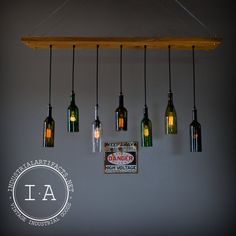 a group of wine bottles hanging from a wooden beam with lights on top of them