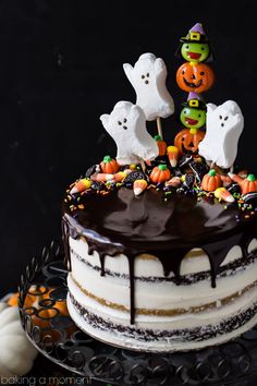 a halloween cake with chocolate icing and sprinkles on top, topped with ghost heads