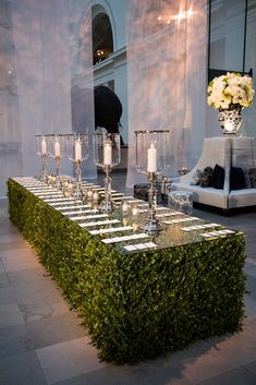 a table set up with candles and centerpieces in the shape of a boxwood hedge