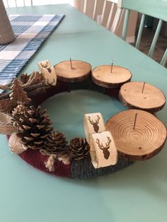 a wreath made out of wood slices and pine cones on a dining room table with blue chairs