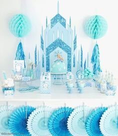 a frozen princess birthday party with blue decorations and paper fan garlands on the table