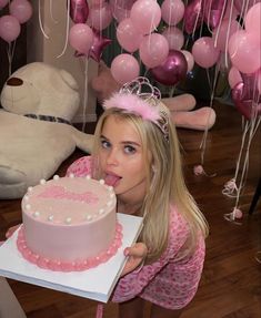 a woman blowing out the candles on her birthday cake with pink balloons in the background