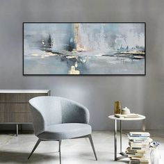 an abstract painting hangs on the wall above a chair and side table in a modern living room