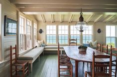 a table and chairs in a room with large windows