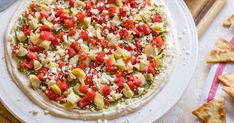 a pizza topped with lots of toppings sitting on top of a white plate next to crackers