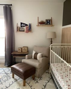 a baby's room with a white crib, brown chair and wooden shelves