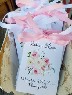 a baby in bloom gift box with ribbon and tags on the front, sitting on a wooden table