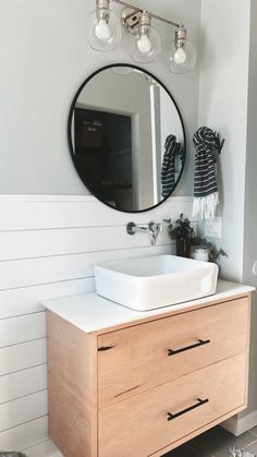 a bathroom with a sink, mirror and lights on the wall in front of it