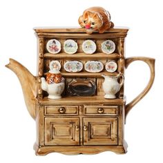 a cat sitting on top of a wooden shelf next to a tea pot and saucer