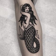 a black and white tattoo of a mermaid on the leg