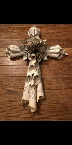 a cross made out of book pages sitting on top of a wooden floor