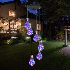 a group of lights that are hanging from a light fixture in the grass near a house