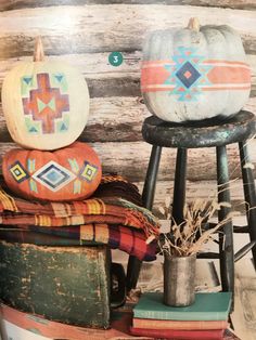 two pumpkins are sitting on top of some books and other decorative items in front of a log wall