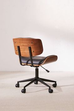 an office chair with wheels and a wooden back rests on a white floor in front of a wall