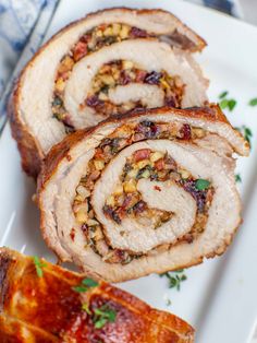 sliced pork loin sitting on top of a white plate with garnishes