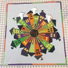 a quilted table topper with an image of buildings and cats on it's center