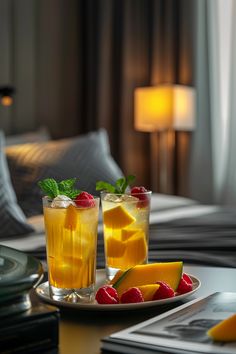 two glasses filled with drinks sitting on top of a table next to plates of fruit