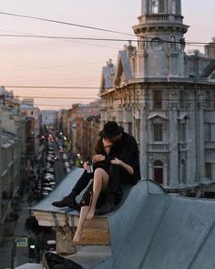 a man and woman sitting on top of a building