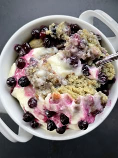 a close up of a bowl of food with berries and ice cream in it on a table