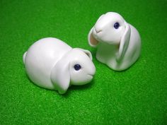 two white plastic animals sitting on top of a green surface