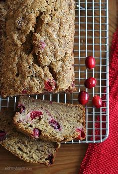 a loaf of cranberry bread sitting on top of a cooling rack next to some cherries