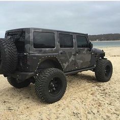 a black jeep parked on top of a sandy beach