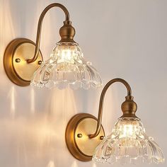 two wall lights with clear glass shades on them