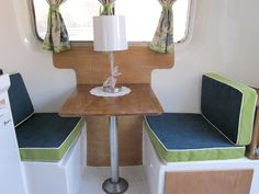 the inside of a camper with two seats and a table in front of it