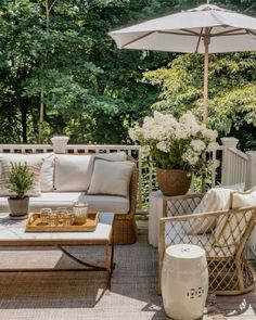 an outdoor living area with wicker furniture and white flowers on the table under an umbrella