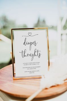 a sign that reads, diaper thoughts on top of a wooden table with feathers