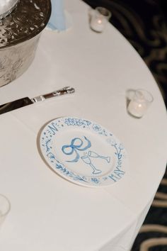 a white table topped with a blue and white plate next to a silver canister