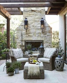 an outdoor living room with stone fireplace and wicker furniture