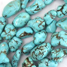 turquoise colored stones are arranged on a white surface with some brown and black speckles