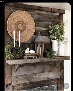 a rustic fireplace mantel decorated with greenery, candles and wicker basket on top