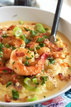 a white bowl filled with shrimp and grits on top of a colorful table cloth