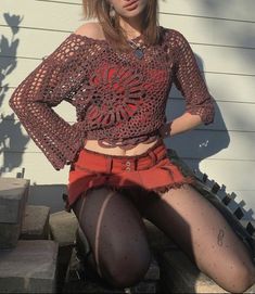 a young woman sitting on the steps wearing short shorts and a crochet top