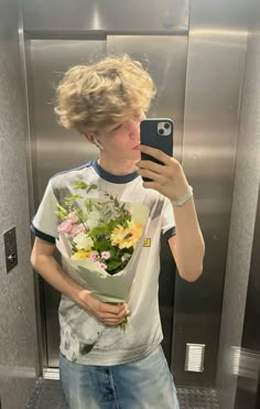 a young man taking a selfie in an elevator with flowers on his t - shirt